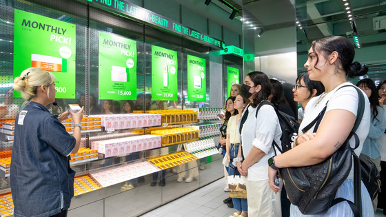 Olive Young staff explains a product to foreign customers at one of its branches. [OLIVE YOUNG]