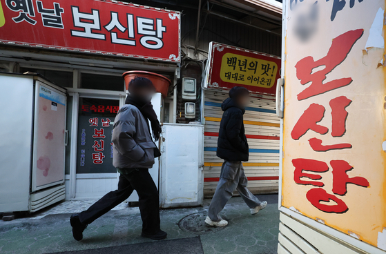 Pedestrians walk by a bosintang (dog meat soup) restaurant in Seoul on Feb. 9. [NEWS1]