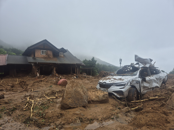 A house with a torn brick wall and a damaged car stands in mid-hill Naeri, Sancheong-eup, around 9:40 a.m. on July 20, following the previous day’s landslide. [KIM MIN-JU] 