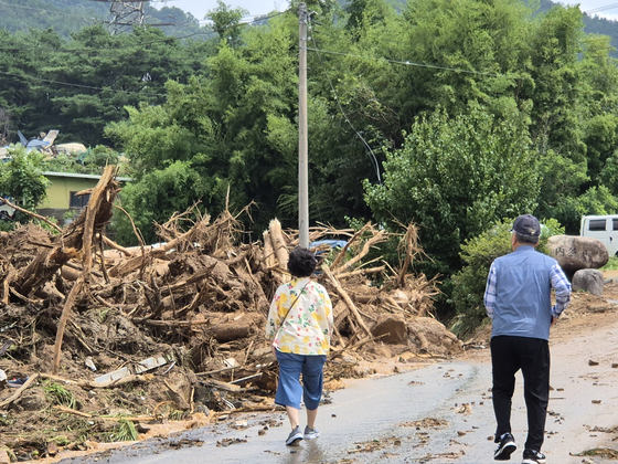A couple in their 70s, relatives of the elderly couple killed in the previous day's landslide, mutter in disbelief while visiting the disaster site in Naebu Village, Sancheong-eup, on the morning of July 20. [AN DAE-HUN]