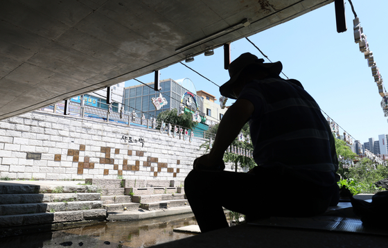 An older person rests in the shade beneath a bridge near Jidong Bridge in Paldal District, Suwon, Gyeonggi, to escape the heat on July 11. [NEWS1]