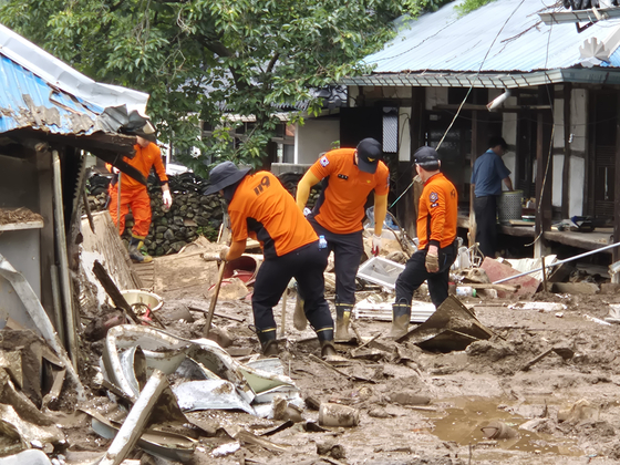 Firefighters dig through a pile of dirt searching for a missing person in Mogo Village in Sancheong, South Gyeongsang, on July 21. On July 19, a man in his 70s went missing after being swept away by landslides during the worst rain in history in the region. [AN DAE-HUN]