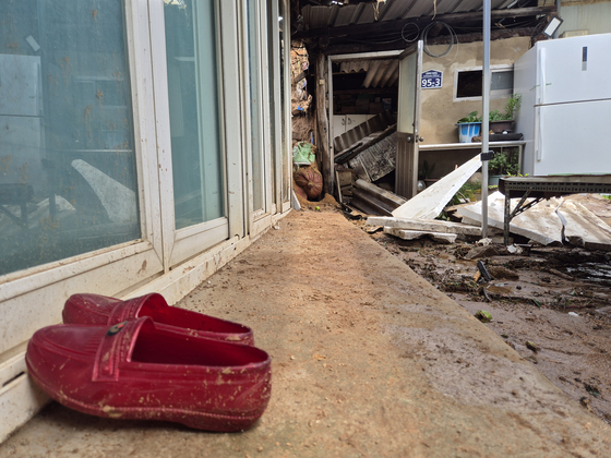 A pair of rubber shoes sits abandoned outside a home in Naebu Village, Sancheong-eup, on July 20. The elderly couple who lived there were killed in a landslide triggered by heavy rain the previous day. [AN DAE-HUN]
