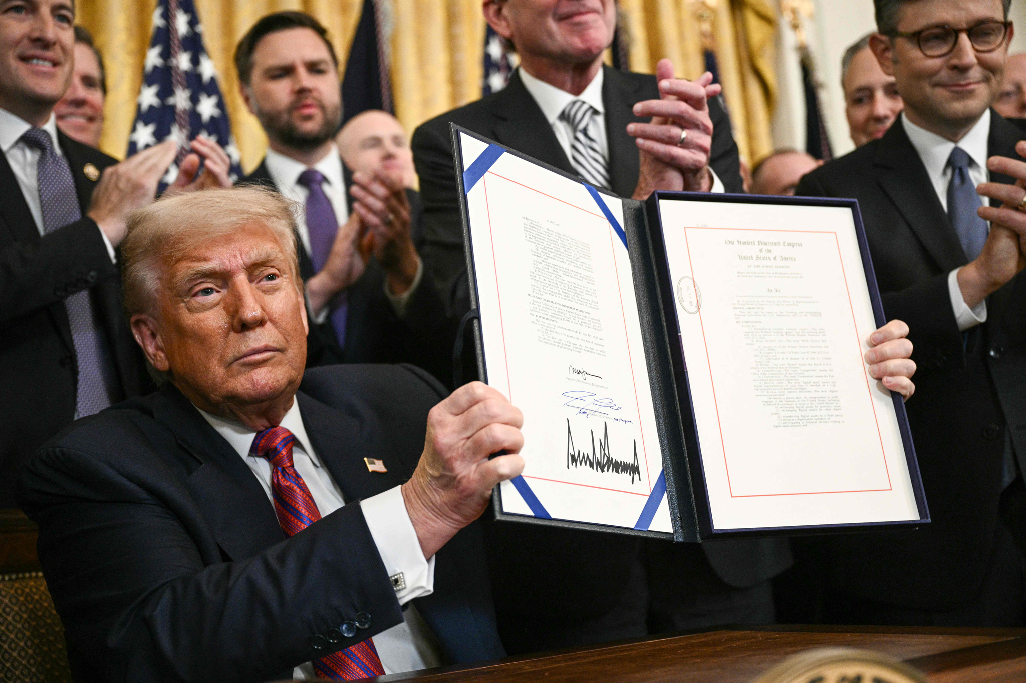 US President Donald Trump displays the GENIUS Act, which codifies the use of stablecoins — cryptocurrencies pegged to stable assets like the dollar or U.S. bonds -- after signing it in the East Room of the White House in Washington on July 18. [AFP/YONHAP]
