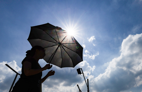 As the heat wave warning continues in Daegu on July 23, a person walks with a parasol at Dongdaegu Station Plaza. [YONHAP]