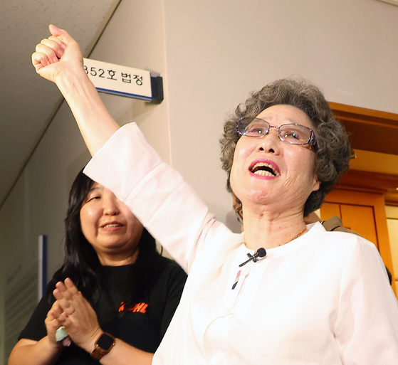 Seventy-eight-year-old Choi Mal-ja, who was found guilty of injuring a man who tried to rape her 61 years ago, holds up her fist in joy as she exits a courtroom at the Busan District Court on July 23 after prosecutors made a public apology toward Choi on the same day. [YONHAP]