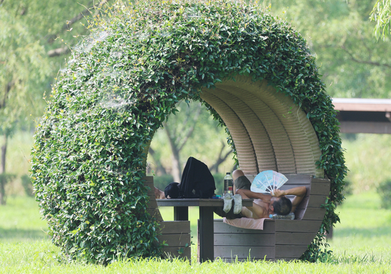 As heat waves broil most of the nation on July 23, a person takes shelter on a shaded bench at Samnak Ecological Park in Sasang District, Busan, in the southern part of Korea. [YONHAP]