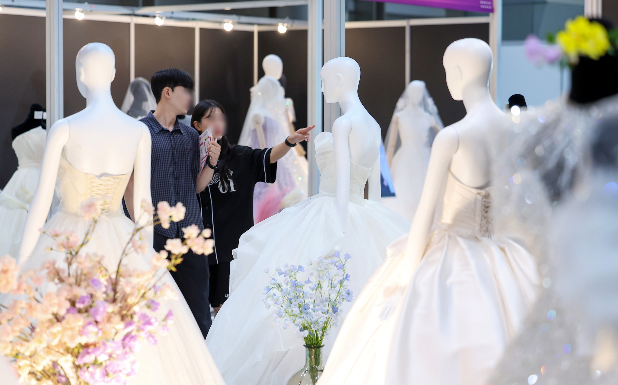 Engaged couples look at wedding dresses during a wedding exposition at Coex in southern Seoul on July 6. [NEWS1]