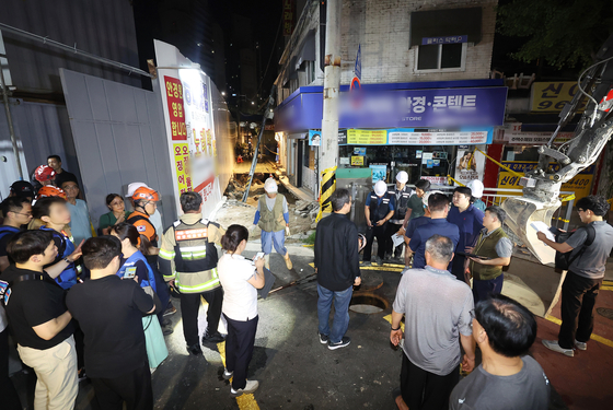 Officials and residents look at a sinkhole that occurred at Dongdaemun District, eastern Seoul, on July 23 evening. [YONHAP]