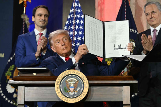 U.S. President Donald Trump displays an executive order on artificial intelligence he signed at the ″Winning the AI Race″ AI Summit at the Andrew W. Mellon Auditorium in Washington on July 23. [AFP/YONHAP]