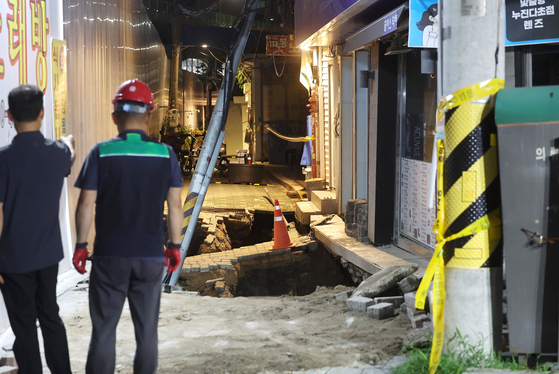 Officials look at a sinkhole that occurred at Dongdaemun District, eastern Seoul, on July 23 evening. [YONHAP]