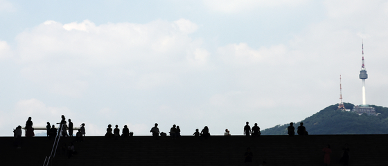 People look up at the blue sky from the steps of the National Museum of Korea in Yongsan District, central Seoul, on July 24, as the city remains under an extreme heat warning. [NEWS1]