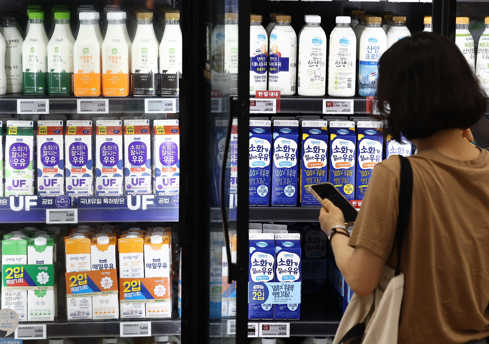  A shopper selects milk at a large supermarket in Seoul on July 27. [YONHAP]