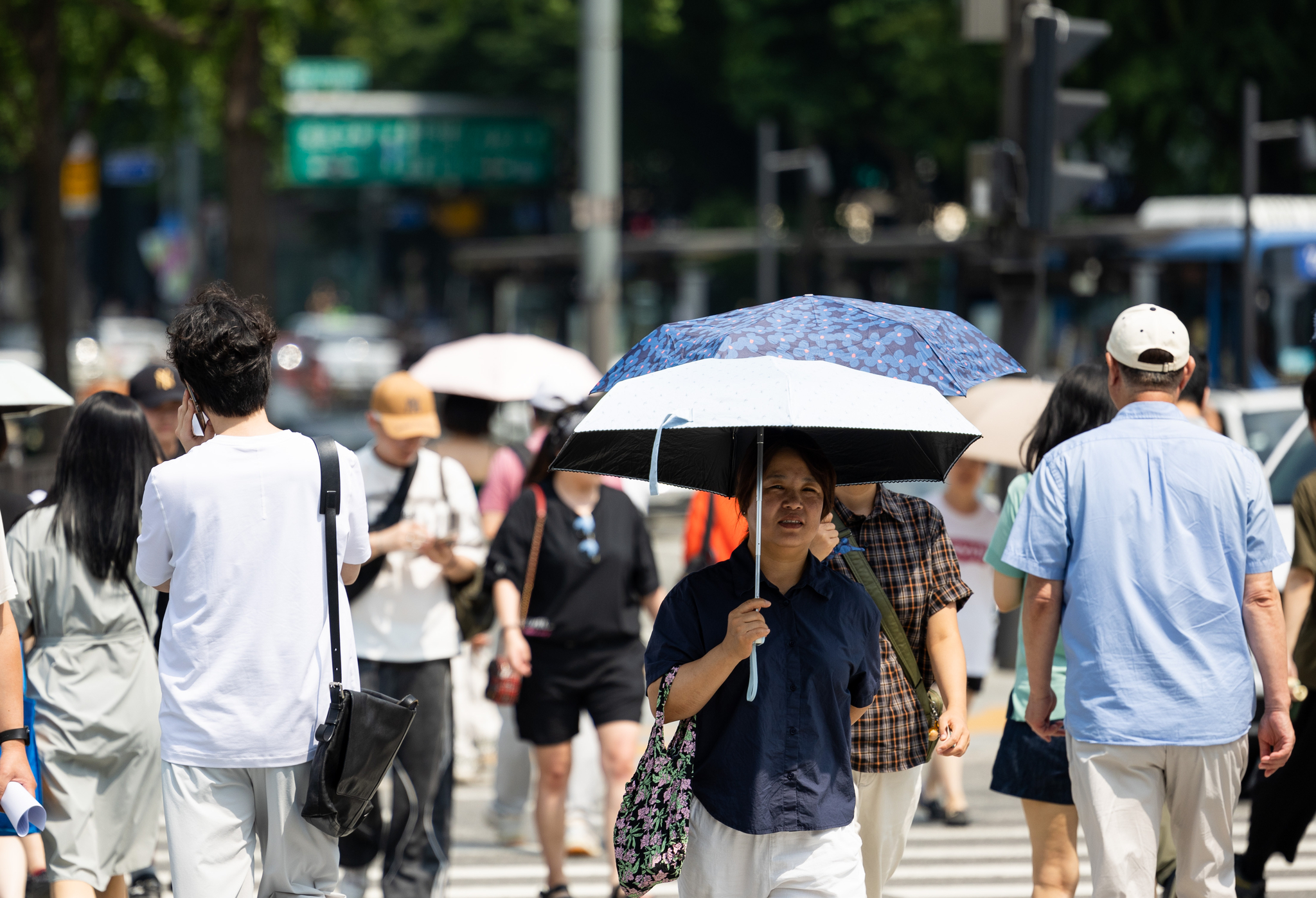 People cross the street at Gwanghwamun Square in central Seoul on July 25 as a heat wave warning remains in effect for most parts of Korea. [JOONGANG ILBO]