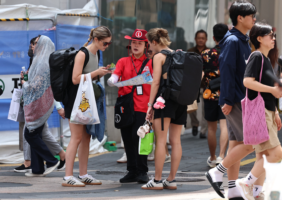 Foreign tourists receive guidance from a tour guide in Jung District, central Seoul, on July 1. [NEWS1] 