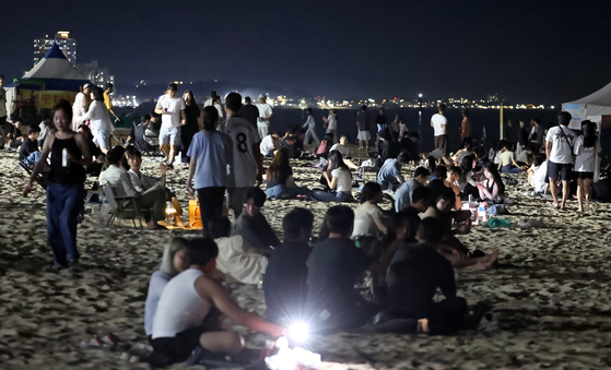 Visitors to a beach in Gangneung, Gwangwon, rest as a tropical night hit the region on July 27. [YONHAP]