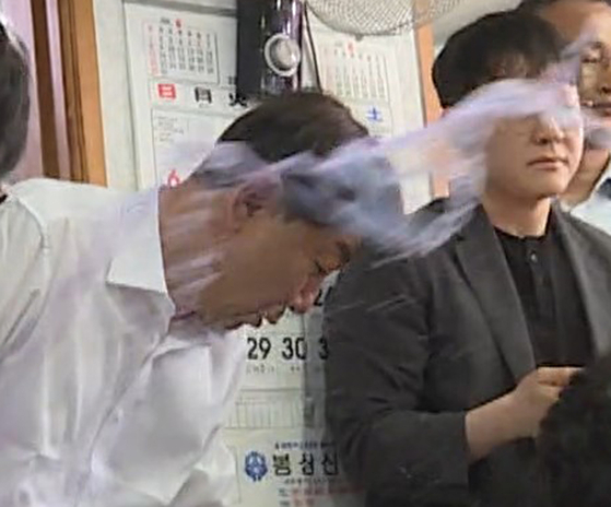 Jeonju Mayor Woo Beom-ki is splashed with water during a public discussion on the proposed Wanju-Jeonju municipal merger at a restaurant in Wanju County, North Jeolla, on July 25. [YONHAP] 