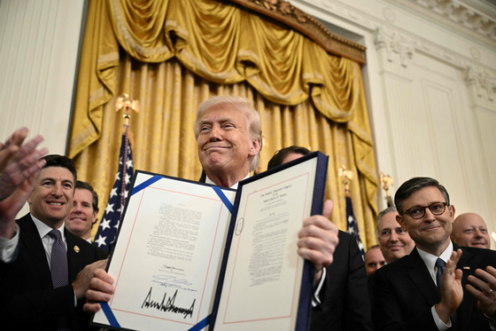 U.S. President Donald Trump displays the GENIUS Act, which codifies the use of stablecoins, after signing it in the East Room of the White House in Washington on July 18. [AP/YONHAP]