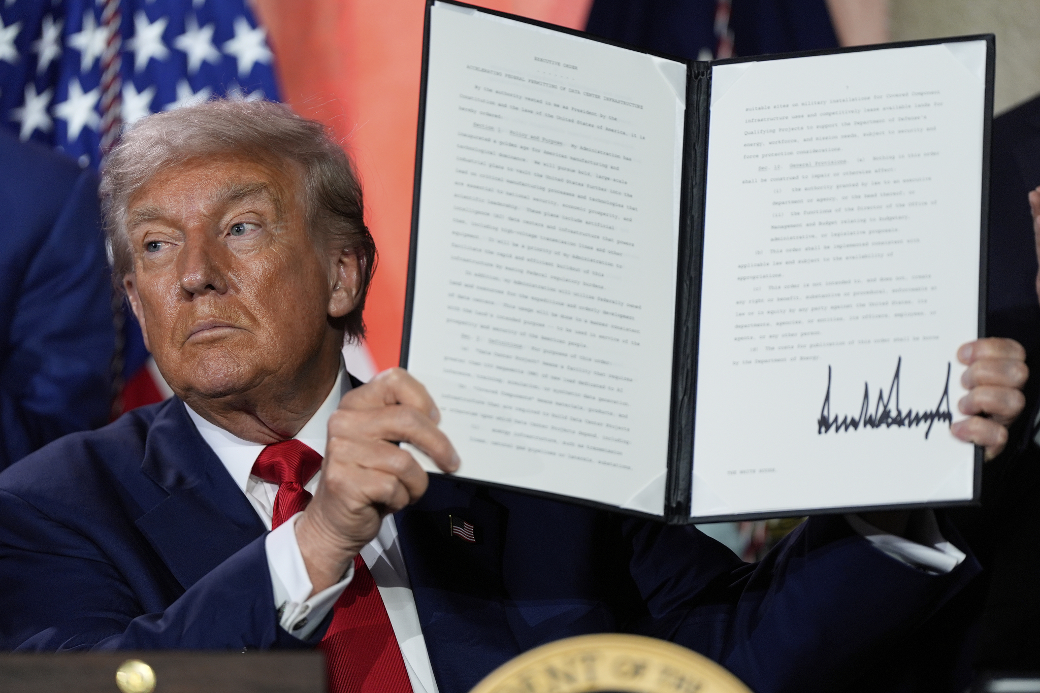 U.S. President Donald Trump holds a signed executive order regarding permitting for AI infrastructure after speaking during an AI summit at the Andrew W. Mellon Auditorium on July 23 in Washington. [AP/YONHAP]