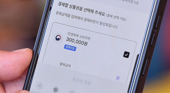 A consumer uses their consumer coupon through a mobile app on July 27 at a retail complex in eastern Seoul's Dongdaemun District. [NEWS1]