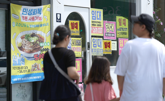 Pedestrians walk by a street in Gyeongsan, North Gyeongsang, on July 27, with an advertisement showing a notice that customers can use consumer coupons at a nearby restaurant. [YONHAP]