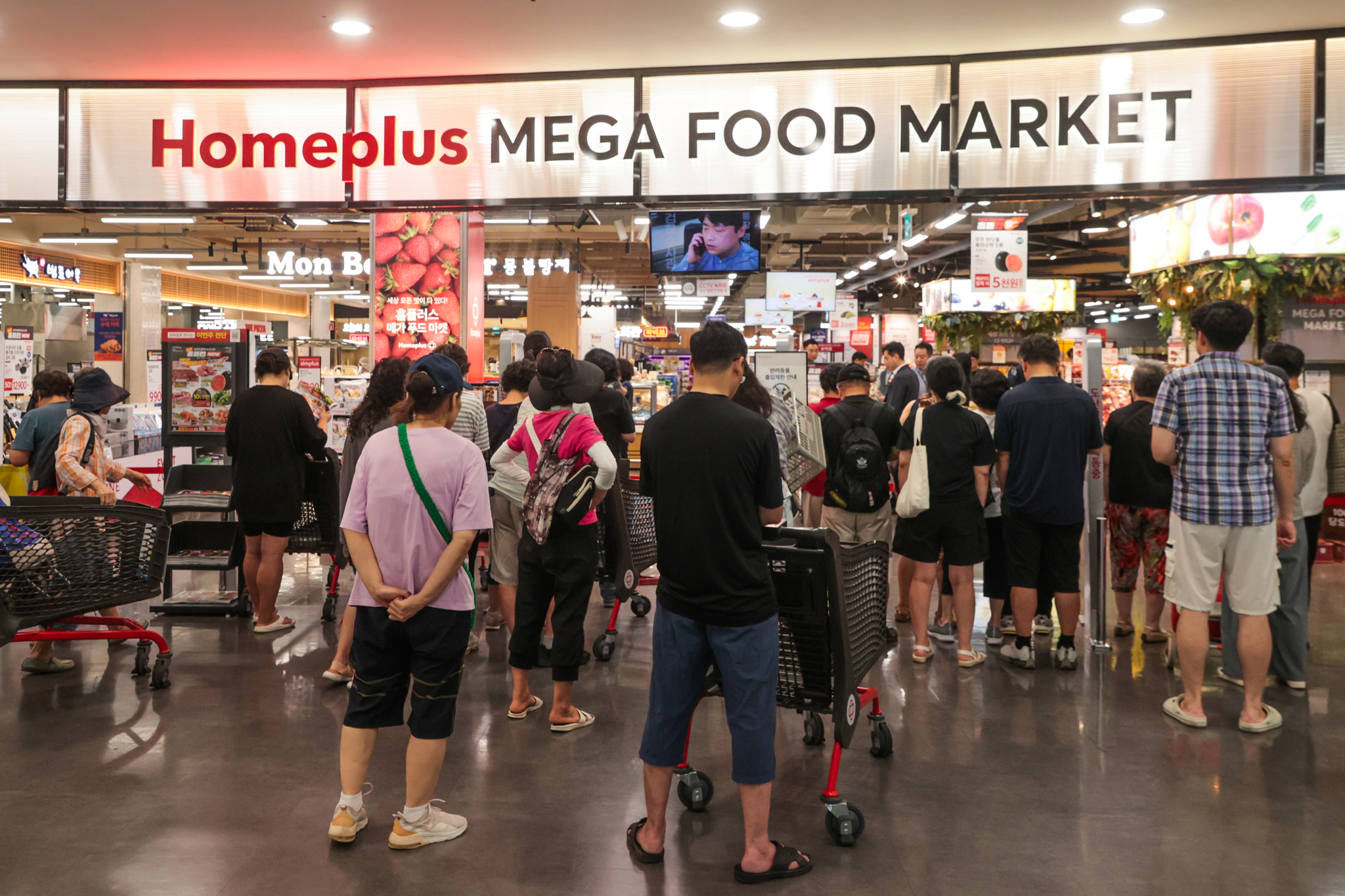 Shoppers wait in line for the opening of the Gangseo branch of Homeplus in western Seoul on July 31 to purchase discounted items at the “Encore Homeplus NOW” sale. With scorching heat driving up the prices of produce, the promotion draws heightened interest from budget-conscious consumers. [YONHAP]