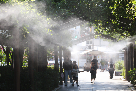 Children cool off in mist from a cooling fog system at the National Debt Redemption Movement Memorial Park in Jung District, Daegu, on July 31. [YONHAP]