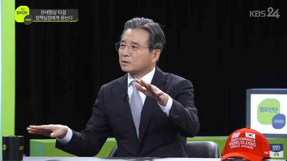 Kim Yong-beom, the presidential policy chief and one of the key figures behind Korea’s recent tariff negotiations with the United States, presents a red baseball cap reading “Make America Shipbuilding Great Again” in English on a KBS talk show on Aug. 3. [SCREEN CAPTURE]
