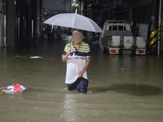 A citizen walks through a flooded road in Unam-dong, Buk District, in Gwangju, on Aug. 3 at night as heavy rain hits the southern regions of Korea. [GWANGJU BUKGU]