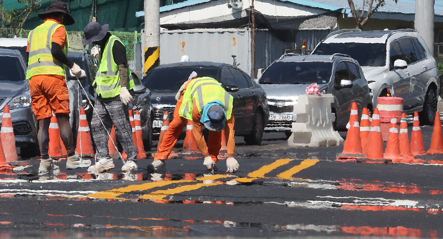 Workers paint the road in Daegu's Suseong District on July 31 amid a heat wave. [YONHAP]