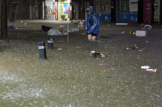 A citizen walks through a flooded road in Unam-dong, Buk District, in Gwangju, on Aug. 3 at night as heavy rain hits the southern regions of Korea. [YONHAP]