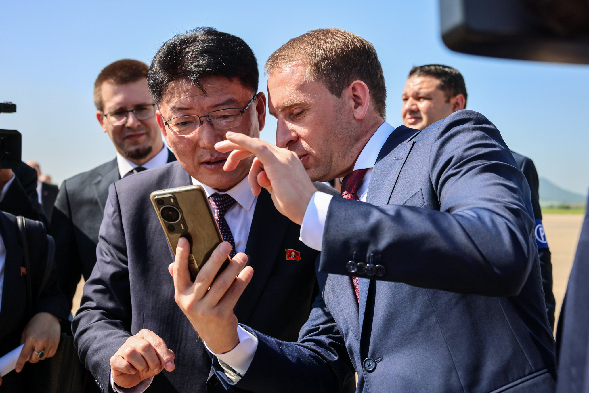 North Korean External Economic Relations Minister Yun Jong-ho, left, and Russian Natural Resources Minister Alexander Kozlov look at a phone together following a ceremony at Pyongyang International Airport on July 28 marking the arrival of the first direct flight from Moscow to the North Korean capital in decades. [AP/YONHAP]