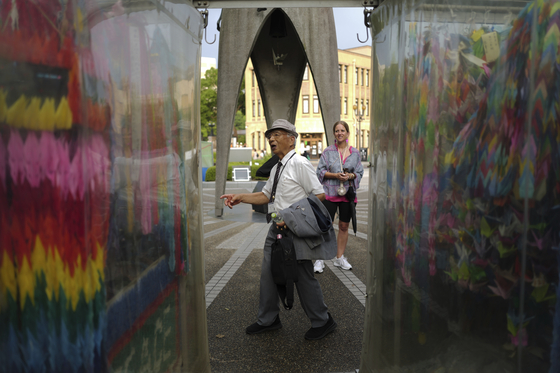 Kunihio Iida, atomic bomb survivor and volunteer guide, speaks in English to foreign visitors in front of the Children's Peace Monument, where people offer paper cranes to honor the victims of the 1945 atomic bomb in Hiroshima, Japan, on July 9. [AP/YONHAP]