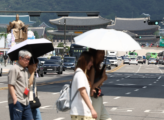 Pedestrians walk with parasols past the Gwanghwamun Square in central Seoul on Aug. 5. [YONHAP]