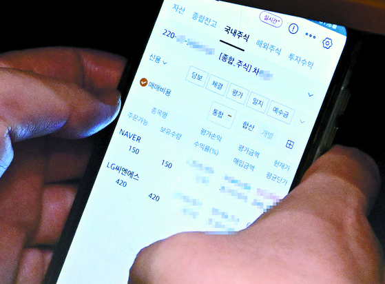 A photo published by The Fact shows Lee Choon-suak, a Democratic Party lawmaker and chair of the National Assembly’s Legislation and Judiciary Committee, checking a trading account registered under an aide's name during a plenary session on Aug. 4. [THE FACT] 