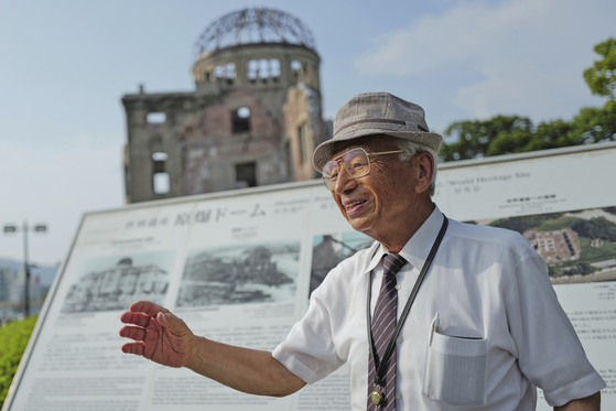 Kunihio Iida, atomic bomb survivor and volunteer guide, speaks in English to foreign visitors in front of the iconic exhibition hall best known as the Atomic Bomb Dome in Hiroshima, Japan, on July 9. [AP/YONHAP]