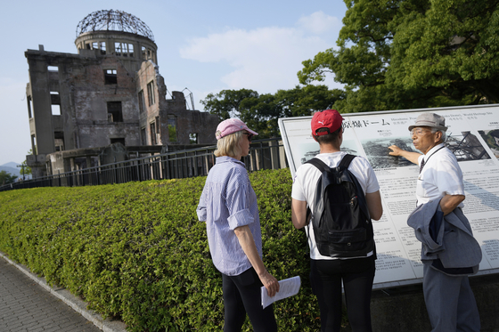 Kunihio Iida, atomic bomb survivor and volunteer guide, speaks in English to foreign visitors in front of the iconic exhibition hall best known as the Atomic Bomb Dome in Hiroshima, Japan, on July 9. [AP/YONHAP]