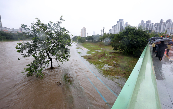 The Yuchon Bridge in western Gwangju is flooded after heavy rain on July 17. [YONHAP]