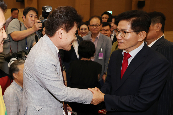 People Power Party leadership candidate Kim Moon-soo shakes hands with conservative YouTuber and former lecturer Jeon Han-gil during a forum at the National Assembly in Yeouido, western Seoul, on Aug. 4. [YONHAP]