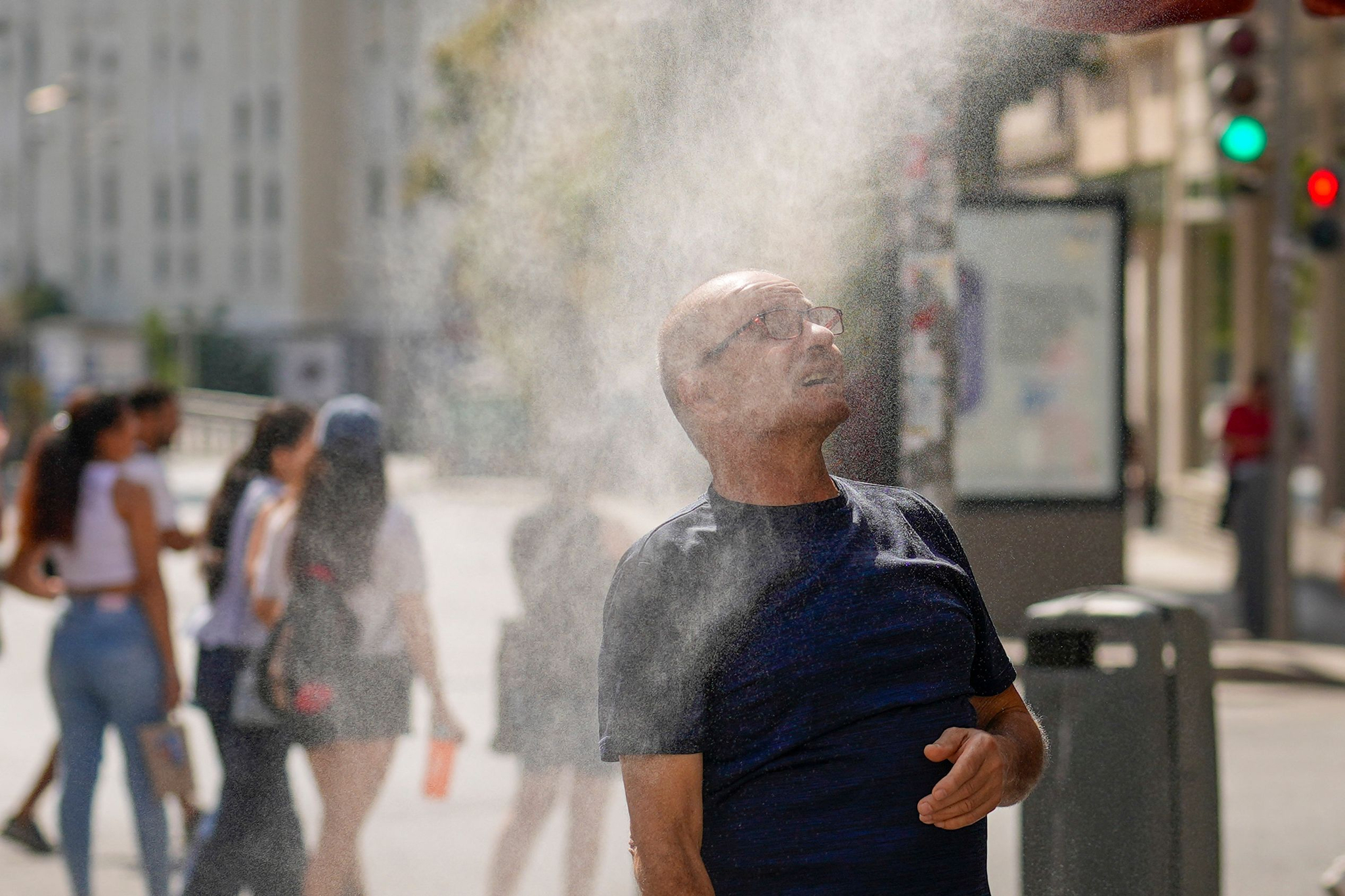 A man reacts as he passes under a cooling mist as temperatures soar during a heatwave in Madrid on August 5. [AFP/YONHAP]