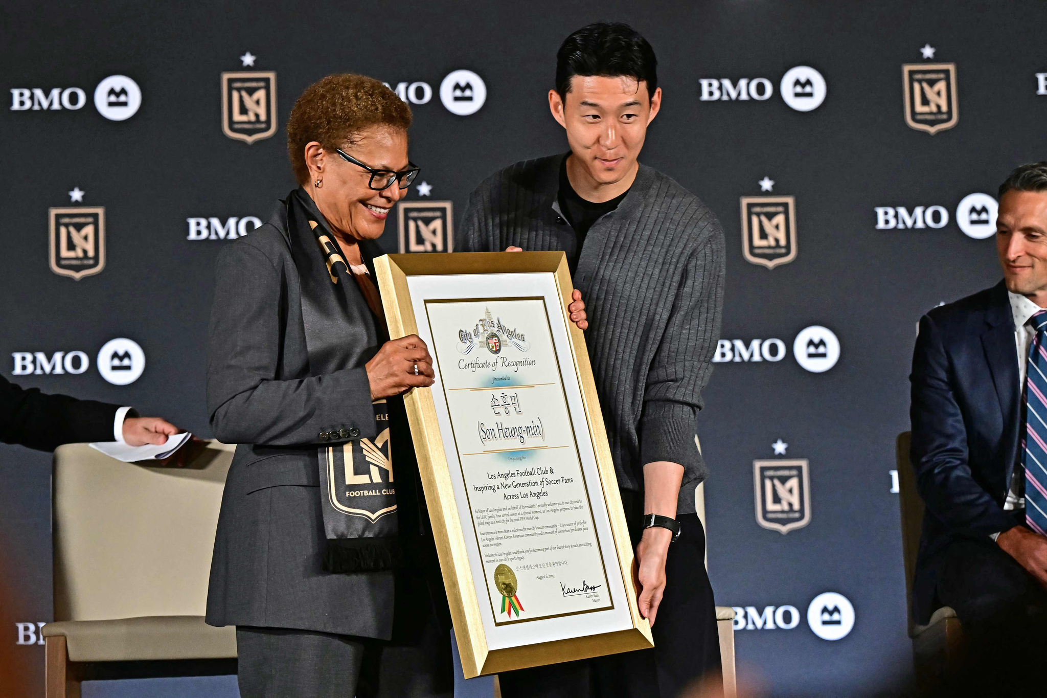Son Heung-min, right, and Los Angeles mayor Karen Bass hold a plaque during a press conference as he joins Los Angeles FC at BMO Stadium's Field Club in Los Angeles on Aug. 6.  [AFP/YONHAP]