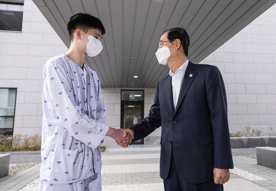 Then-Prime Minister Han Duck-soo, right, shakes hands with Staff Sergeant Pyo Jeong-ho at the Armed Forces Capital Hospital in Seongnam, Gyeonggi, on Oct. 3, 2023. [YONHAP]