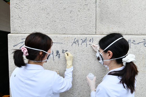 Experts from the National Palace Museum of Korea remove graffiti at Gyeongbok Palace in Jongno District, central Seoul, on Aug. 11. [KOREA HERITAGE SERVICE] 