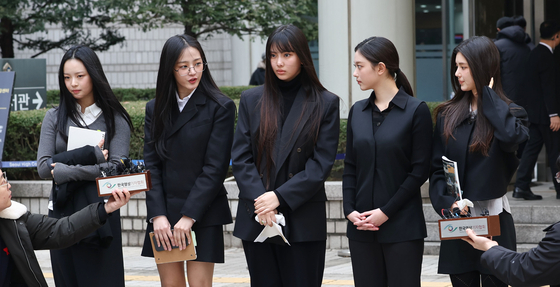 Girl group NewJeans members talk to reporters at the Seoul Central District Court in Seocho District, southern Seoul, on March 7. [YONHAP]