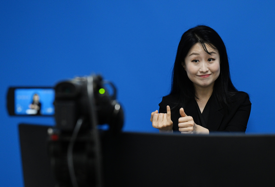 A sign language interpreter relays spokesperson Kang Yu-jung’s press briefing announcing President Lee Jae Myung's visit to the United States for a summit with U.S. President Donald Trump at the Yongsan presidential office in central Seoul on Aug. 12. The presidential office launched simultaneous sign language interpretation service for the first time the previous day. [JOINT PRESS CORPS]
