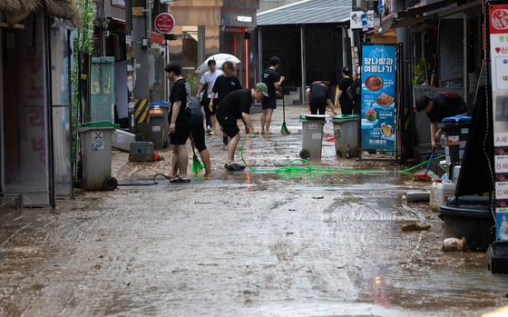 Merchants and shop owners clean a street after heavy rain near Yeonsinnae Station in Eunpyeong District, northern Seoul, on Aug. 13. [NEWS1]