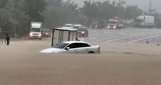 A driver leaves their flooded vehicle on Hwarang-ro in Deogyang District, Goyang, Gyeonggi, on Aug. 13. [YONHAP]