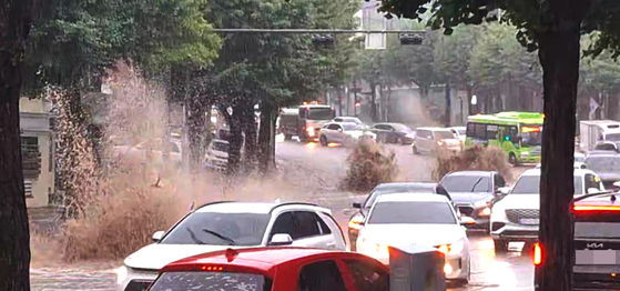 Sewage water bursts out from manholes in Jongno District, central Seoul, on Aug. 13. [YONHAP]