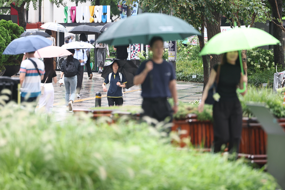 People walk in the rain near Gwanghwamun Square in Jongno District, central Seoul, on Aug. 14. [NEWS1]