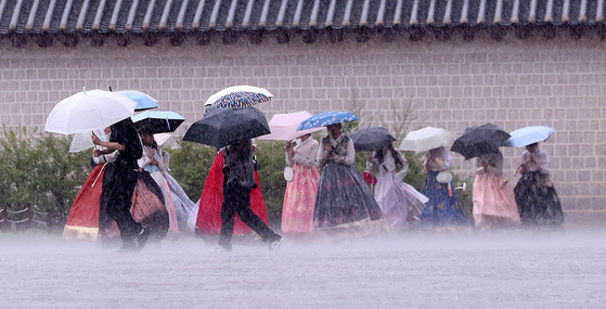 Tourists walk in the rain near the National Palace Museum of Korea in Jongno District, central Seoul as heavy rains fell in the metropolitan area on Aug. 13. [NEWS1]